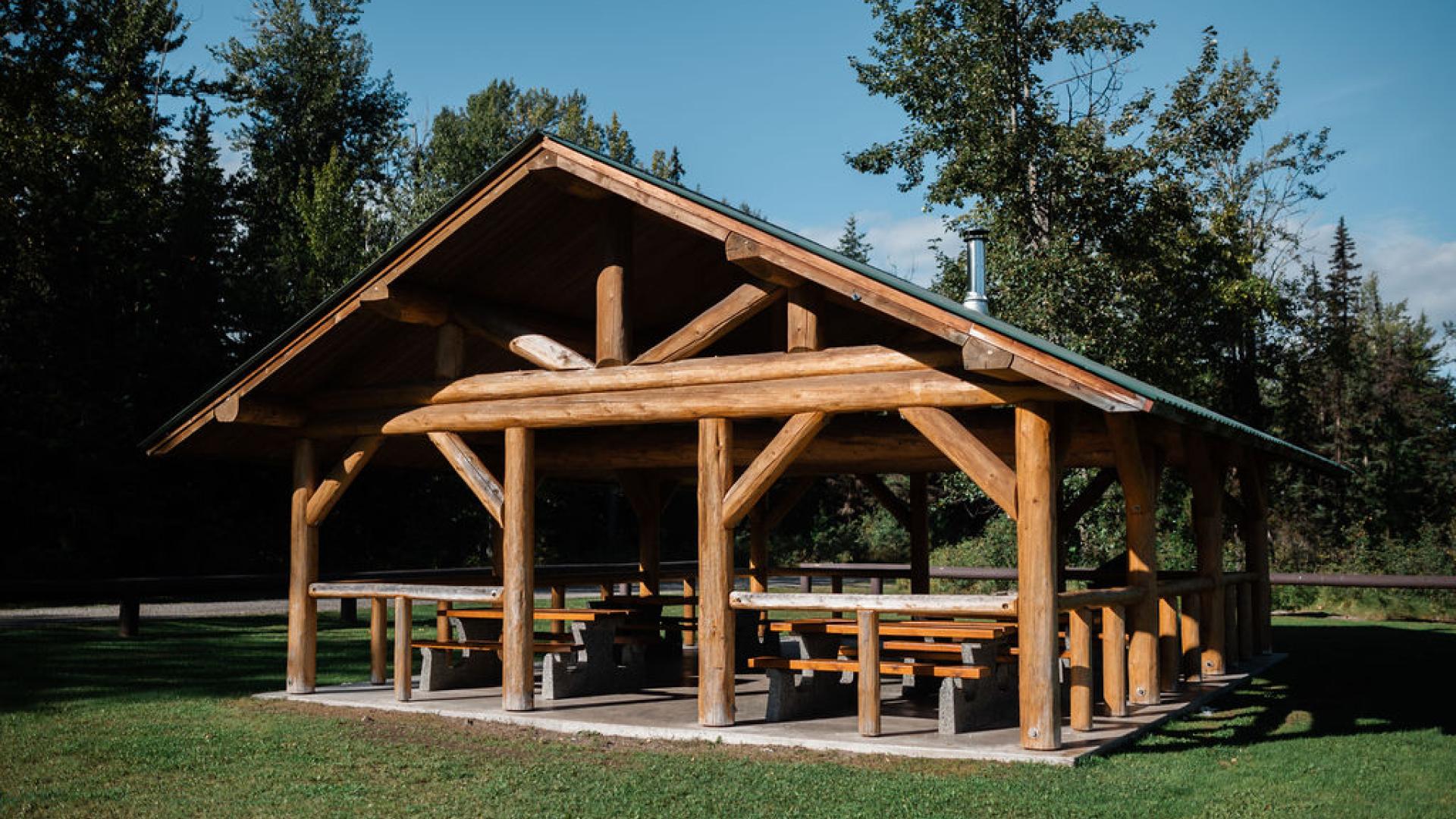 log picnic shelter with picnic tables and a wood stove