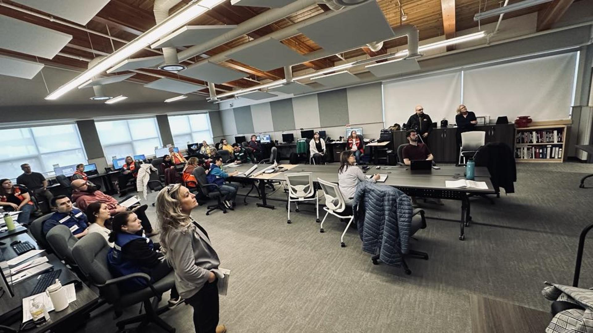 group of people in a meeting room watching a video screen
