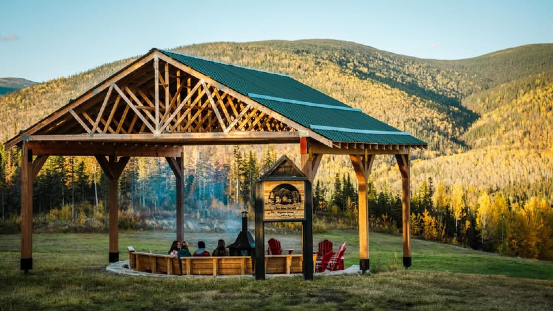 a group of people sitting around a firepit under a gazebo