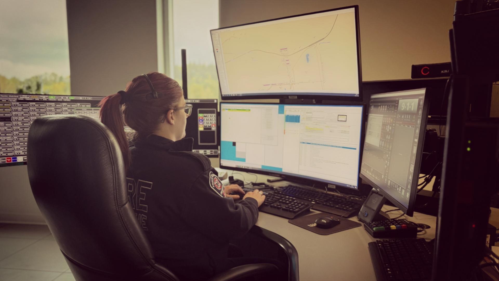 person sitting in front of three computer screens