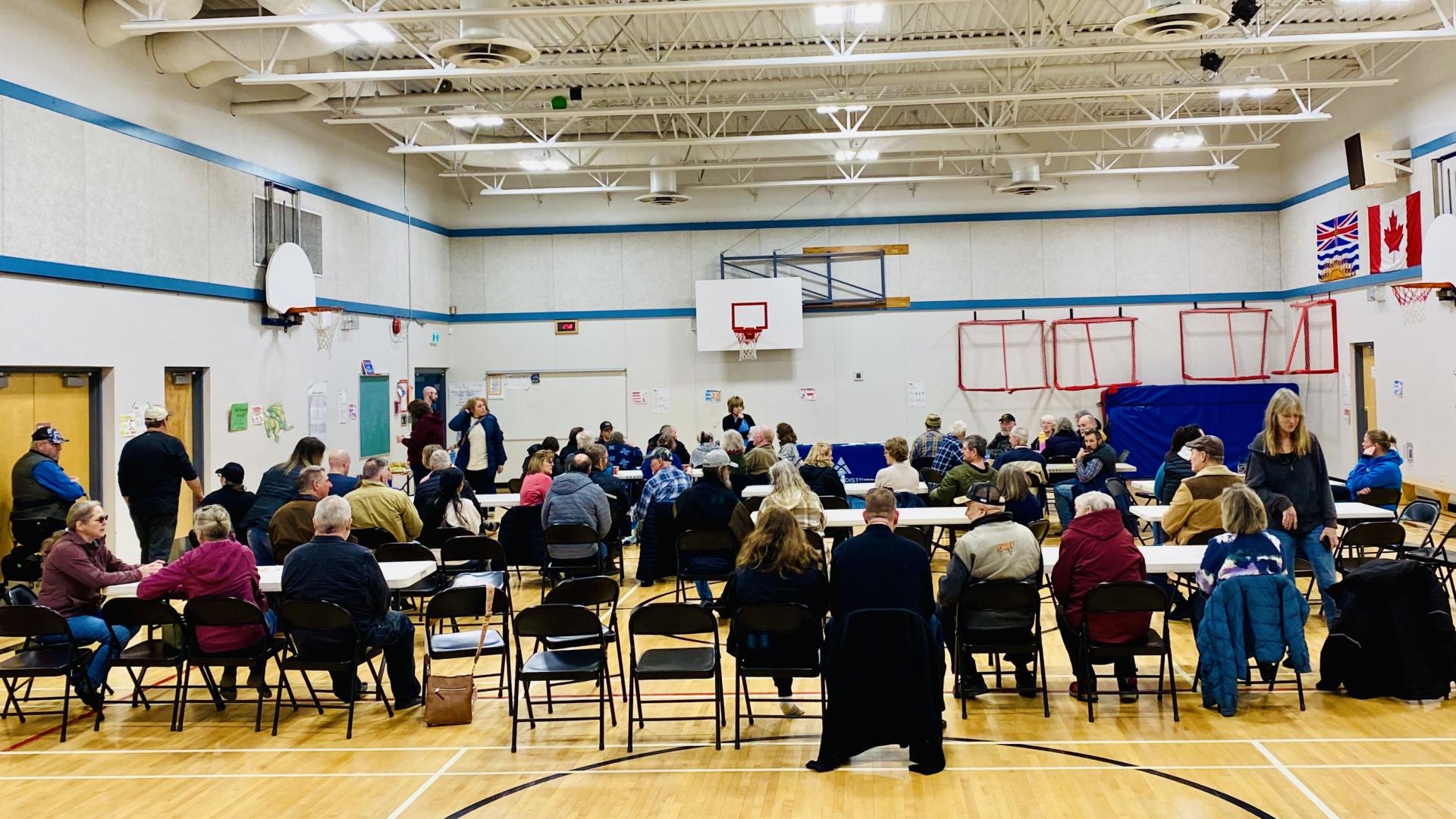 a group of people sitting on chairs in a school gym