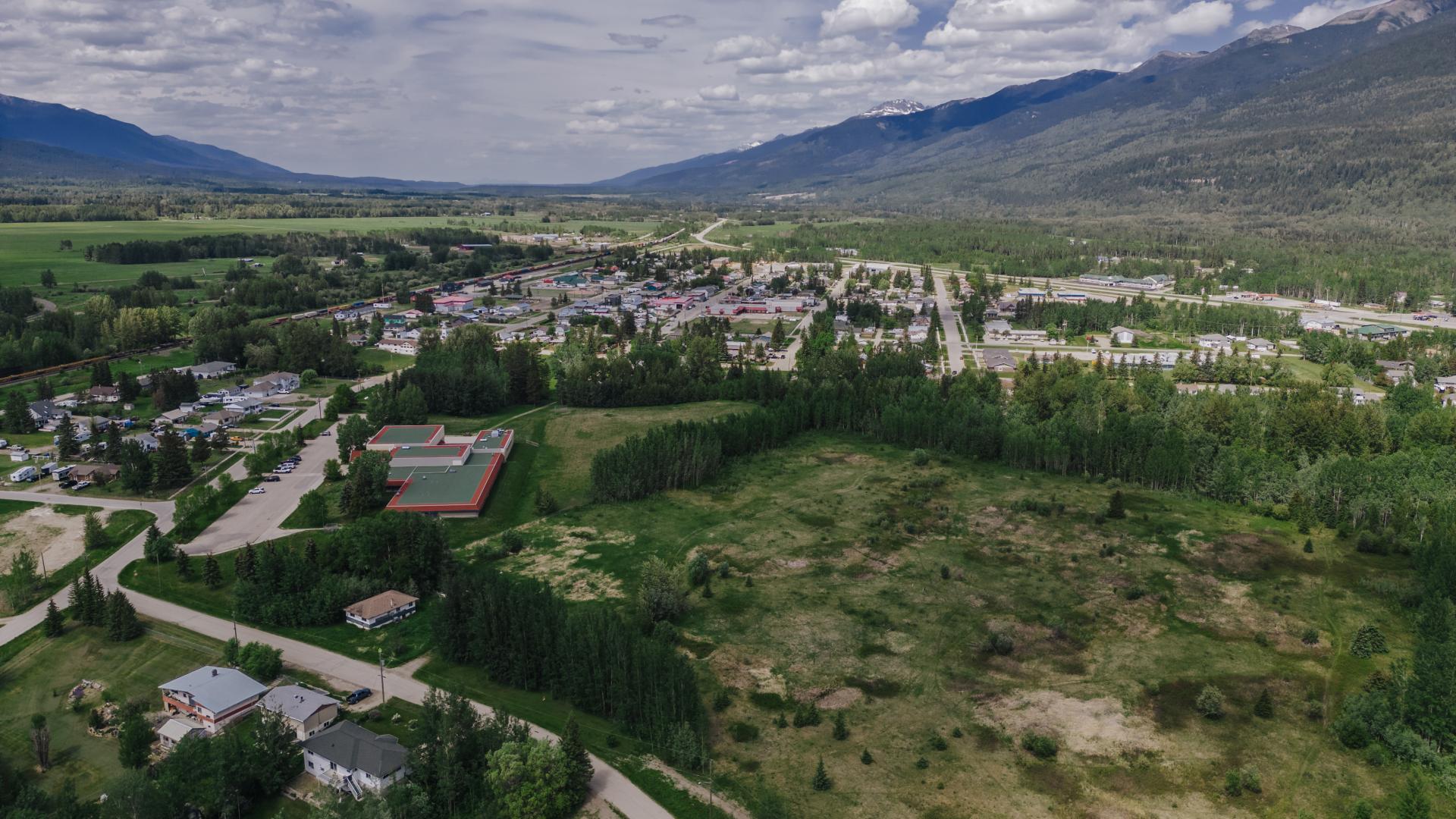 aerial view of a small town surrounded by mountains, grass and trees