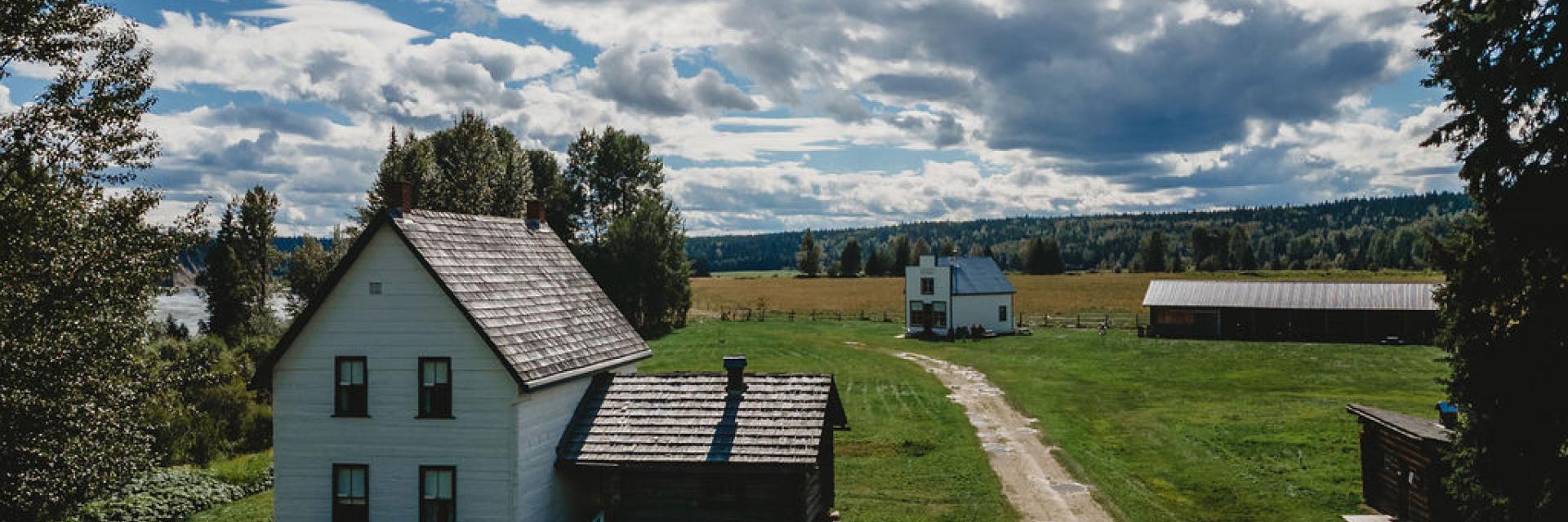 two white wooden farmhouse buildings in a grass field