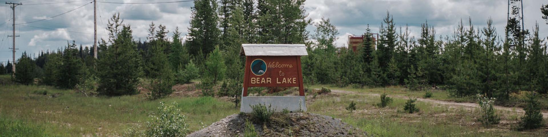Bear Lake wooden community sign in a grass field surrounded by evergreen trees